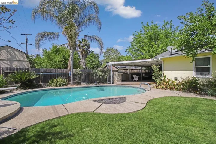 View of swimming pool with patio surround and a fenced backyard