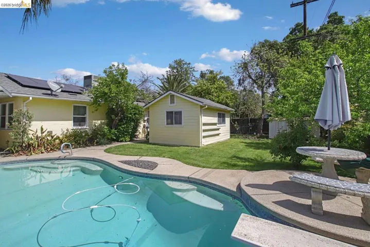 Outdoor pool with a patio, an outdoor structure, and a fenced backyard