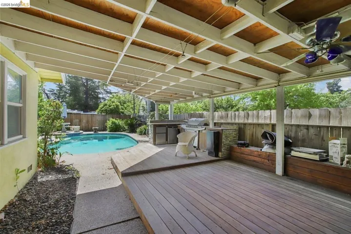 View of pool featuring a wooden deck, area for grilling, a fenced backyard, and a diving board