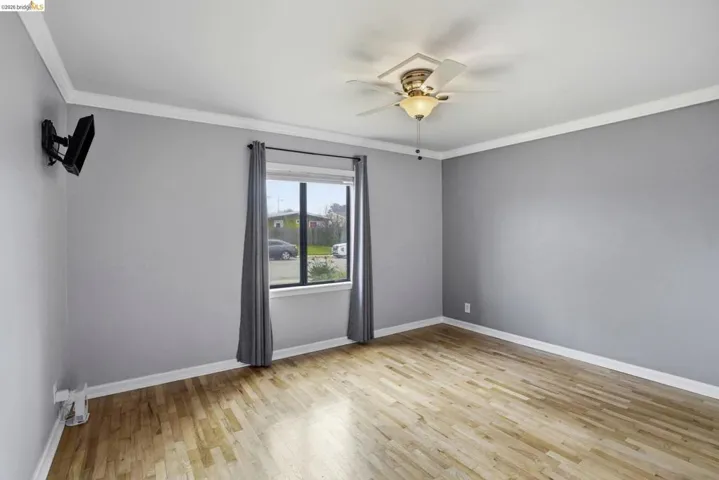 Unfurnished room with light wood-type flooring, a ceiling fan, and ornamental molding