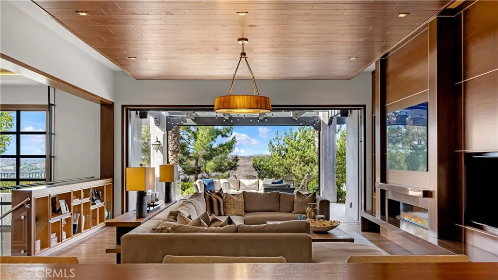 The great room blends style and function with walnut ceilings, a designer fireplace and panoramic sliding doors that open to reveal a backyard worthy of a 5 star resort. Note the wood ceilings and cabinets-- an example of current designs new trend--organic modernism.