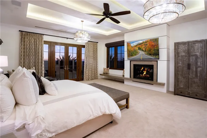 The primary suite is a serene sanctuary with its own balcony, a custom wood-paneled fireplace, motorized sunset shades and dual walk-in closets with built-ins.