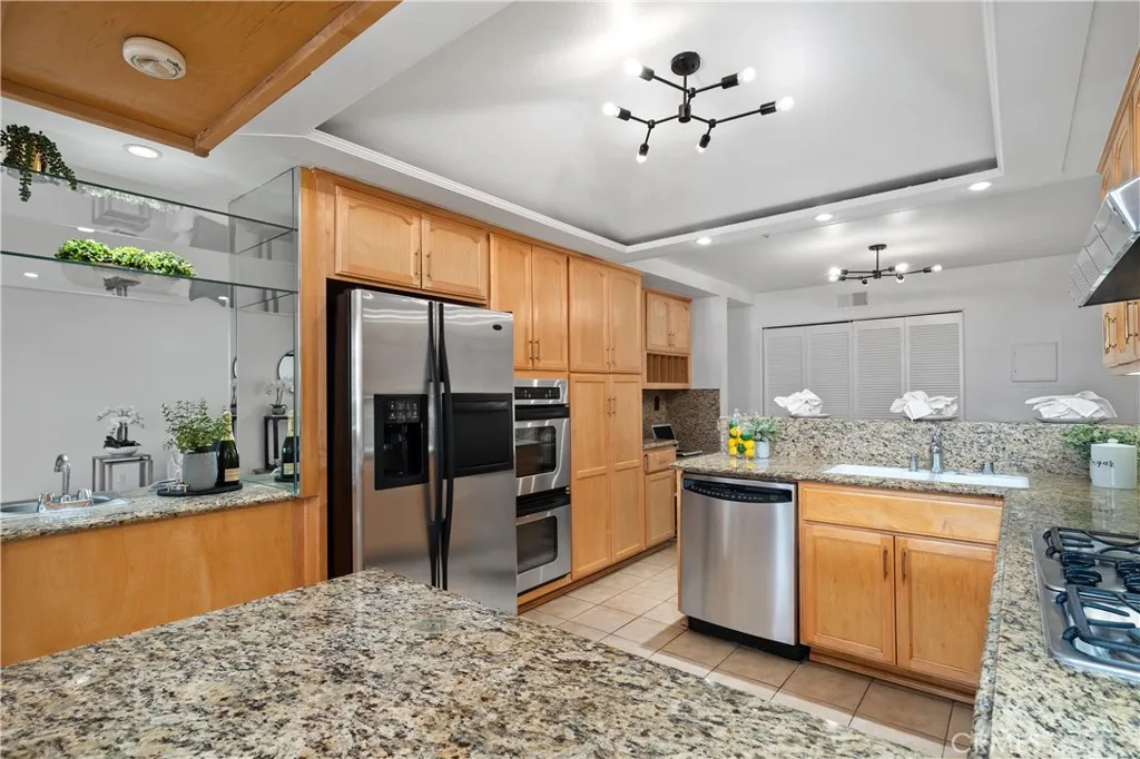 The kitchen features access to wet bar, refrigerator, dual ovens, granite countertops, coffered ceiling with integrated lighting, breakfast bar seating, built in desk & wine rack, and more.