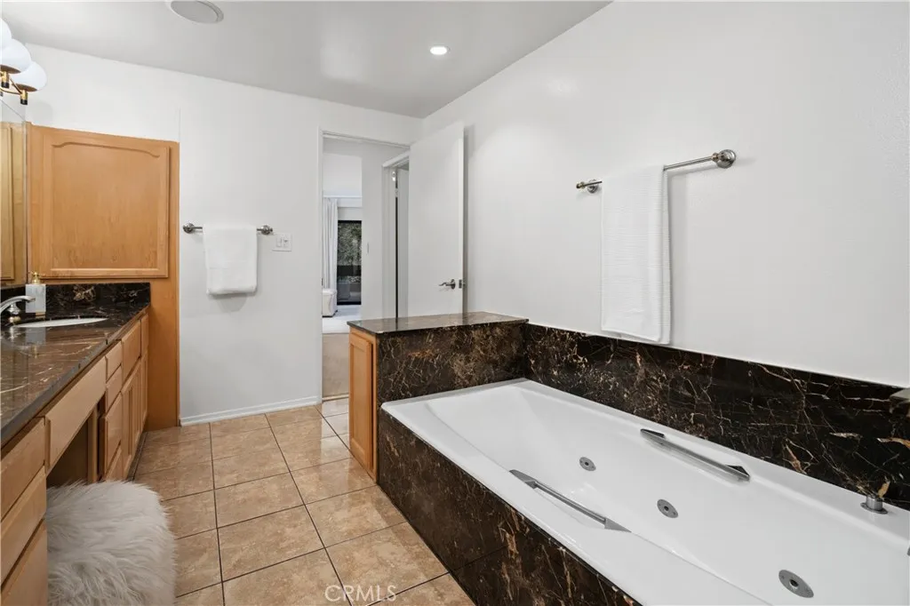 The spa inspired bath features an oversized jetted soaking tub, dual sinks with a seated vanity, separate shower area, and private water closet.