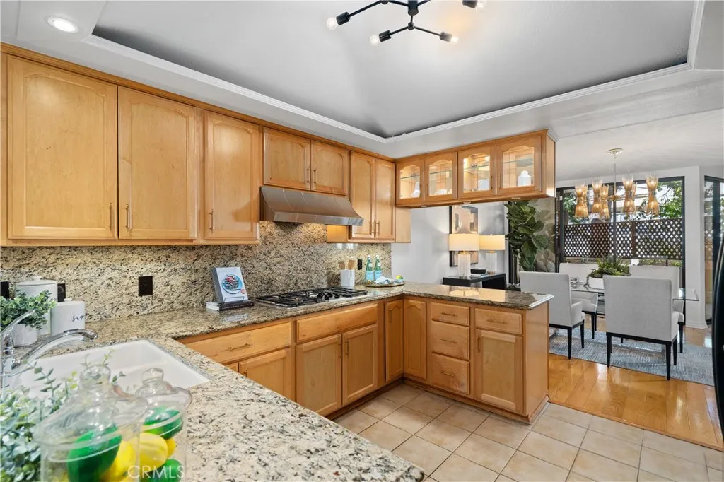 The kitchen features glass front cabinetry with integrated lighting, stainless hood, GE Profile cooktop, and more.