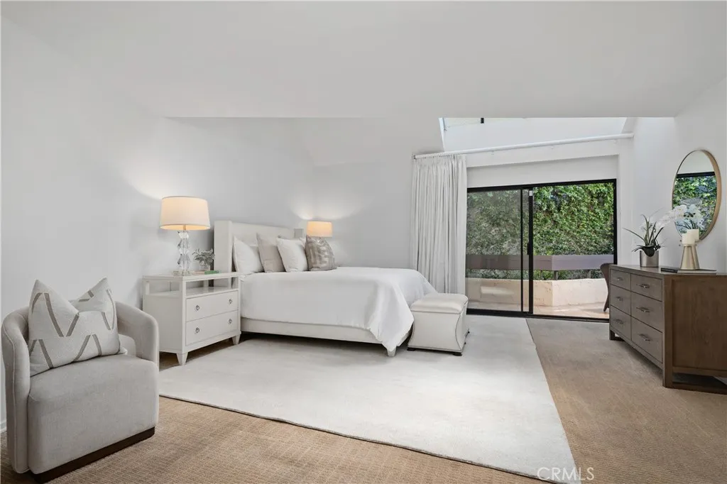 Double door entry into the large primary bedroom includes high ceiling with skylights and sliding doors out to the back balcony.