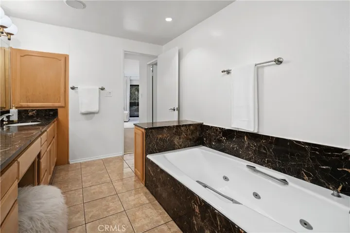 The spa inspired bath features an oversized jetted soaking tub, dual sinks with a seated vanity, separate shower area, and private water closet.