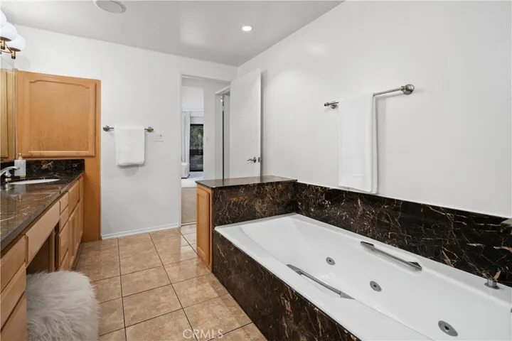 The spa inspired bath features an oversized jetted soaking tub, dual sinks with a seated vanity, separate shower area, and private water closet.
