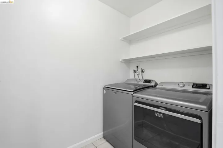 Laundry room with washing machine and clothes dryer and light tile patterned floors