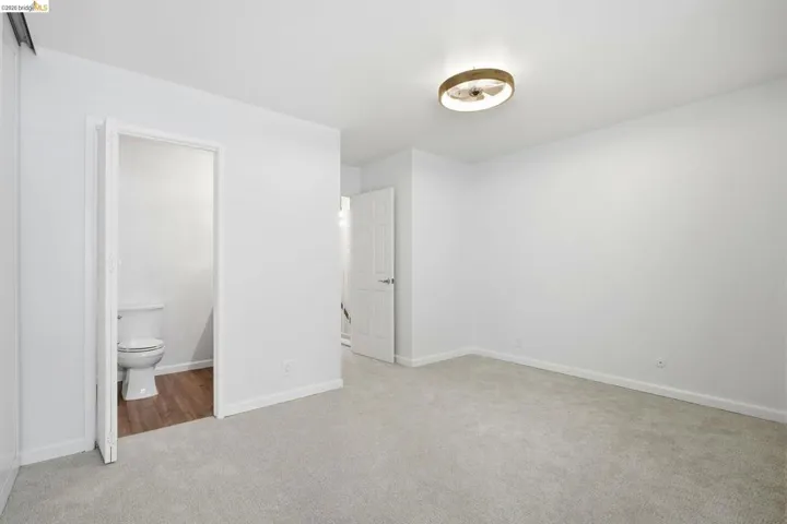 Unfurnished bedroom with light colored carpet and ensuite bath