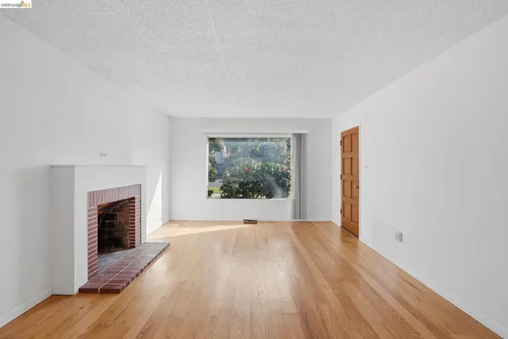 Unfurnished living room featuring a fireplace, a textured ceiling, and light wood-type flooring