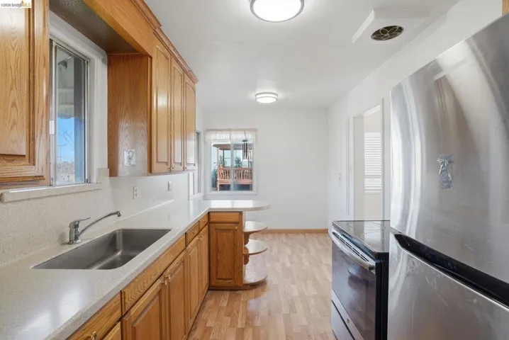 Kitchen featuring stainless steel appliances, light wood-style floors, open shelves, a peninsula, and wood finish cabinetry