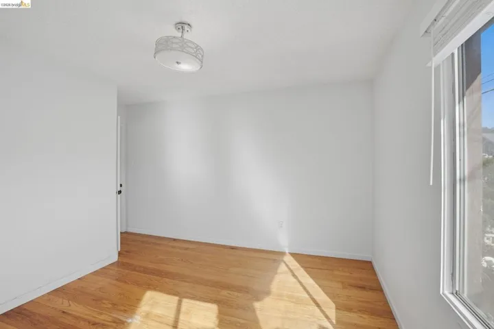Empty room featuring light wood-type flooring and a textured ceiling