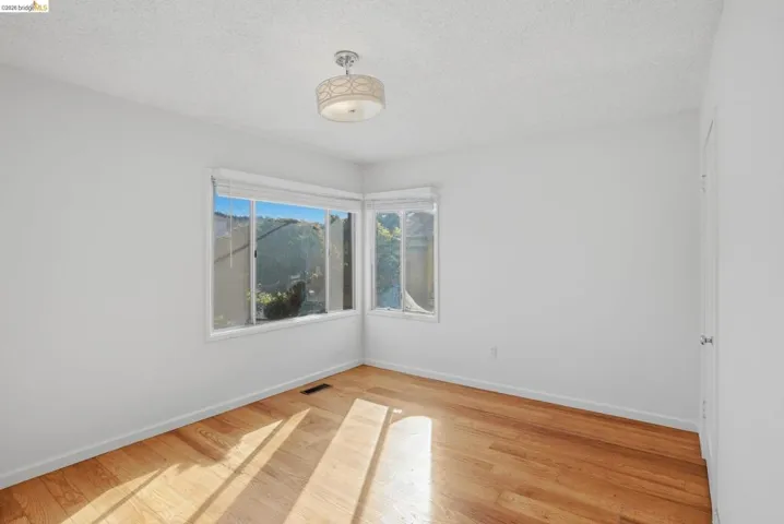 Empty room with light wood-style flooring and a textured ceiling
