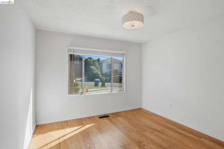 Unfurnished room with light wood finished floors and a textured ceiling