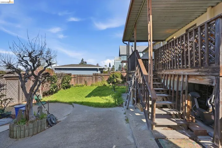 Fenced backyard featuring a wooden deck and a patio
