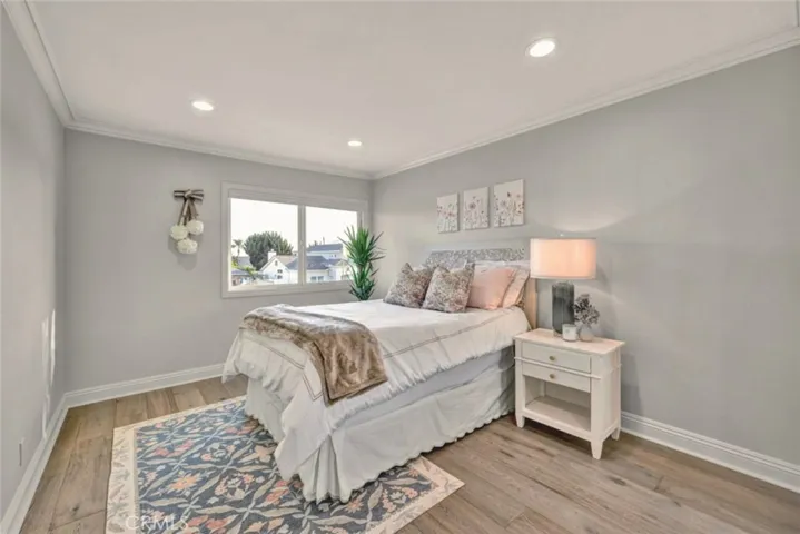 Spacious bedroom with engineered wood flooring, recessed lighting, and abundant natural light.