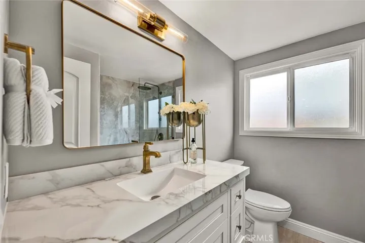 Beautifully updated bathroom featuring granite countertops, modern lighting, and elegant finishes.