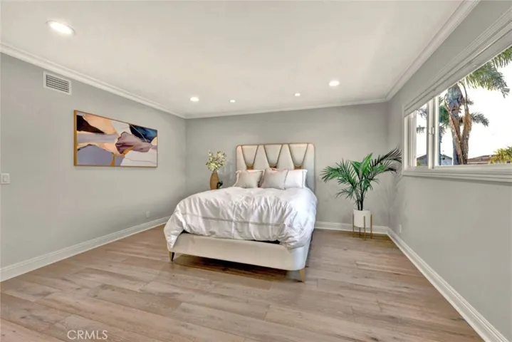 Expansive primary bedroom retreat with engineered wood flooring and recessed lighting.