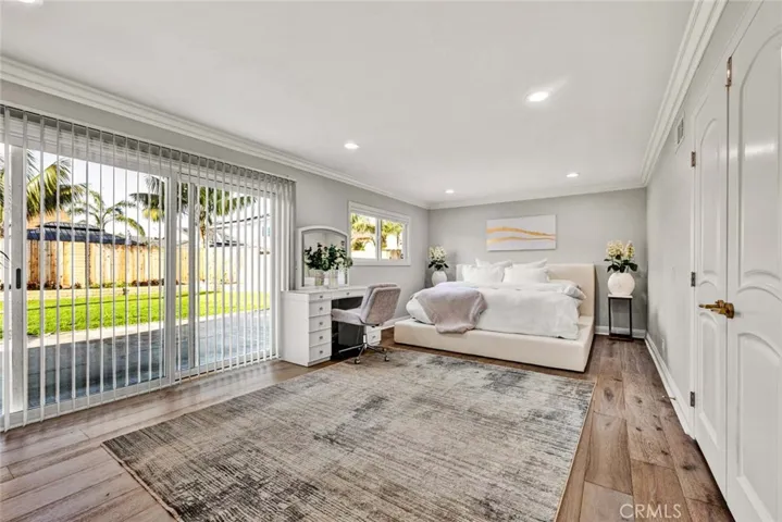Bright bedroom with engineered wood flooring and large window for natural light.