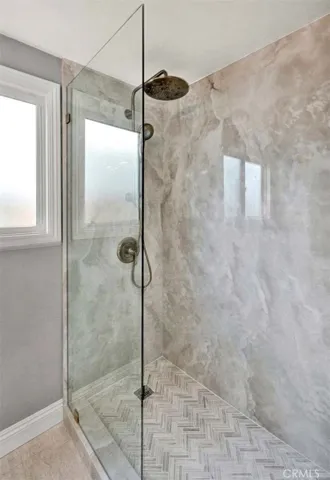 Custom walk-in shower with full slab surround, frameless glass enclosure, and designer rainfall shower fixture.