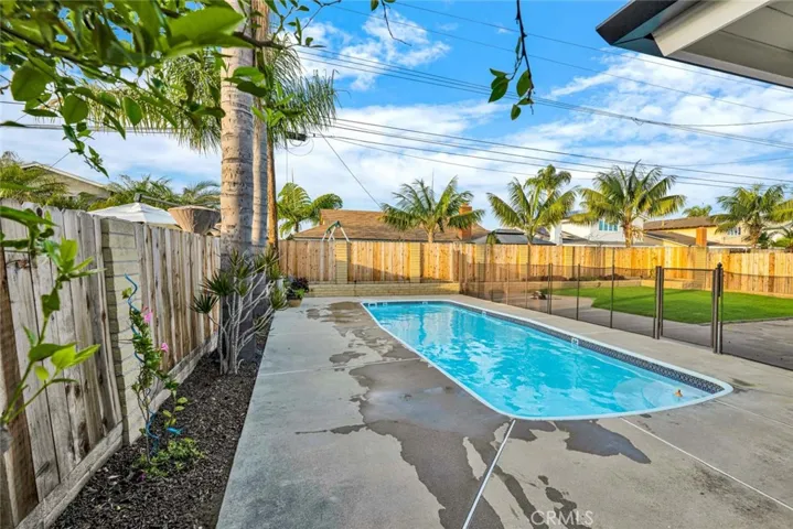 Private backyard retreat with pool, patio space, and mature palm trees creating a relaxed coastal setting.