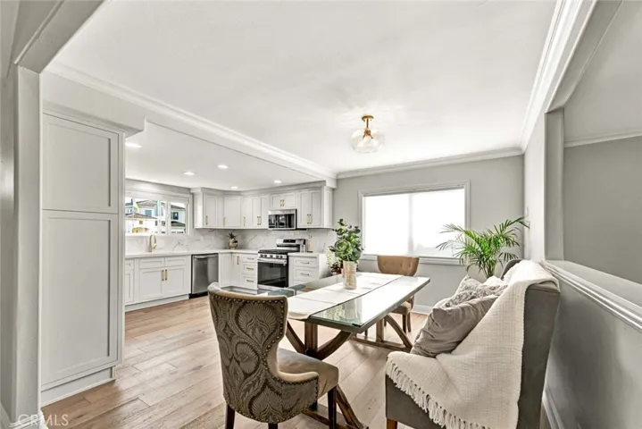 Open dining area flowing into the beautifully remodeled kitchen with quartz countertops, recessed lighting, and engineered wood flooring.