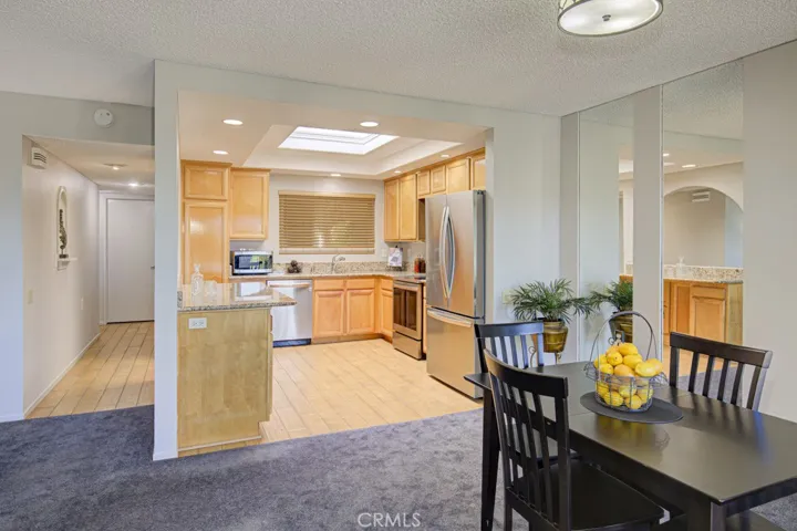 View to kitchen and large skylight from the dining area.Property is unfurnished - staging furniture in photo.