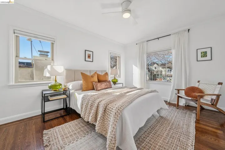 Bedroom with ornamental molding, dark wood-type flooring, multiple windows, and a ceiling fan