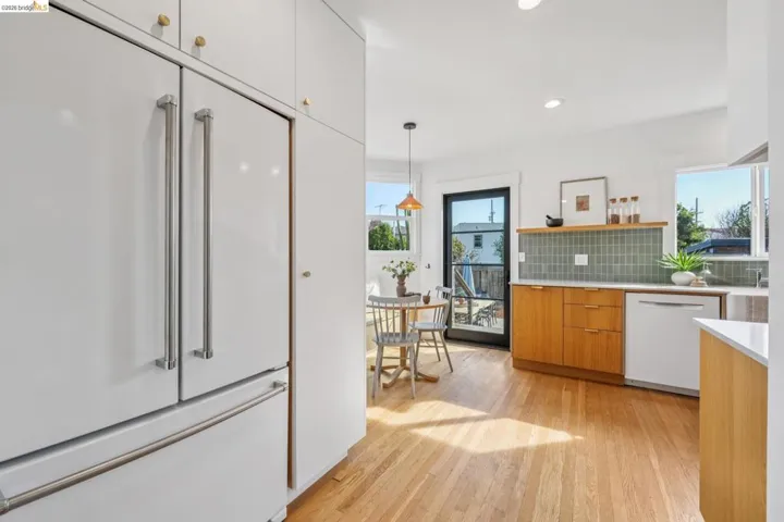 Kitchen with white appliances, open shelves, light wood finished floors, modern cabinets, and backsplash