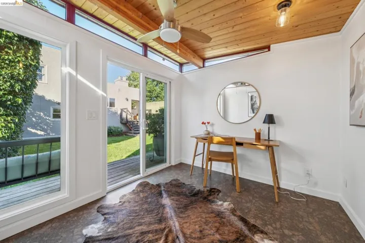 Carpeted home office featuring a wooden ceiling with exposed beams and a ceiling fan