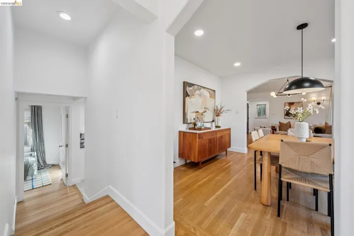 Hallway with arched walkways, light wood-type flooring, and recessed lighting