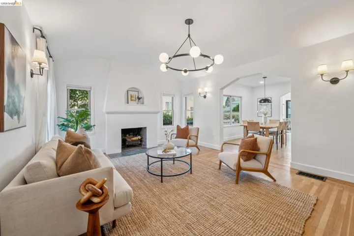 Living room featuring arched walkways, light wood finished floors, suspended lighting, a fireplace, and lofted ceiling