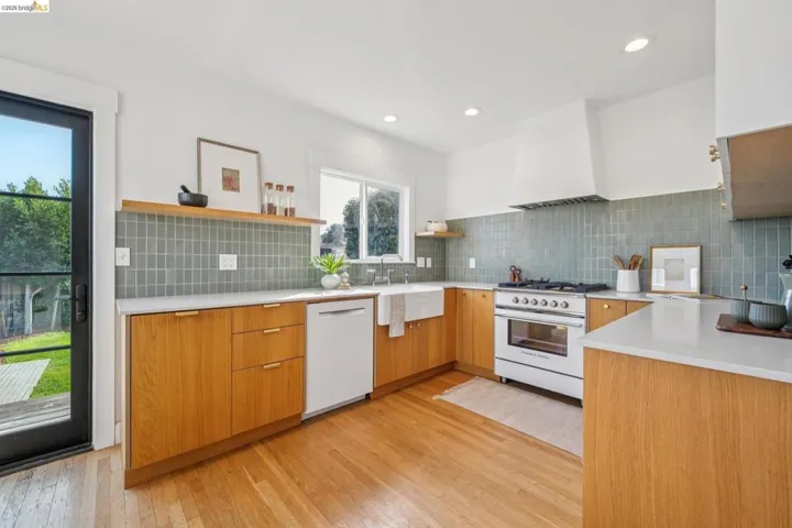 Kitchen featuring open shelves, gas range oven, dishwasher, light wood-style flooring, and modern cabinets