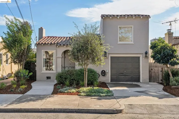 Mediterranean / spanish-style house featuring a tile roof, stucco siding, driveway, a garage, and a chimney