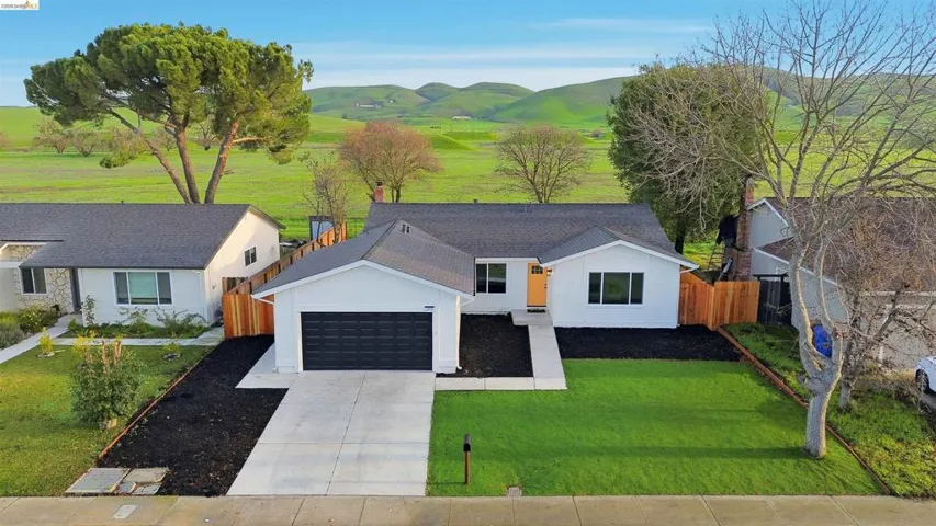 View of front facade with concrete driveway, an attached garage, a shingled roof, and a mountain view