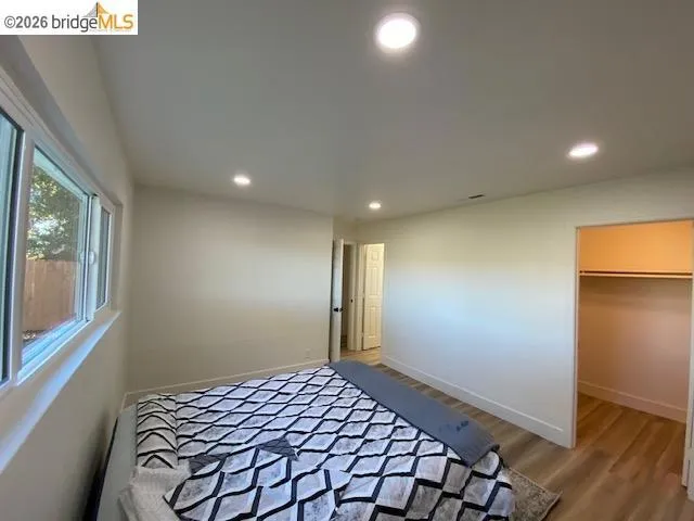 Bedroom featuring a spacious closet, light wood-style floors, and recessed lighting