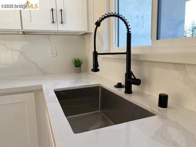 Kitchen view of light stone countertops, white cabinets, and tasteful backsplash
