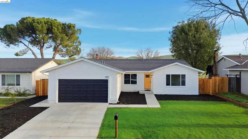 Ranch-style home with concrete driveway, an attached garage, stucco siding, and roof with shingles