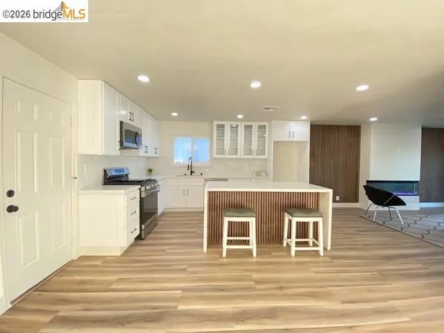 Kitchen with a center island, white cabinetry, stainless steel appliances, glass fronted cabinets, and recessed lighting