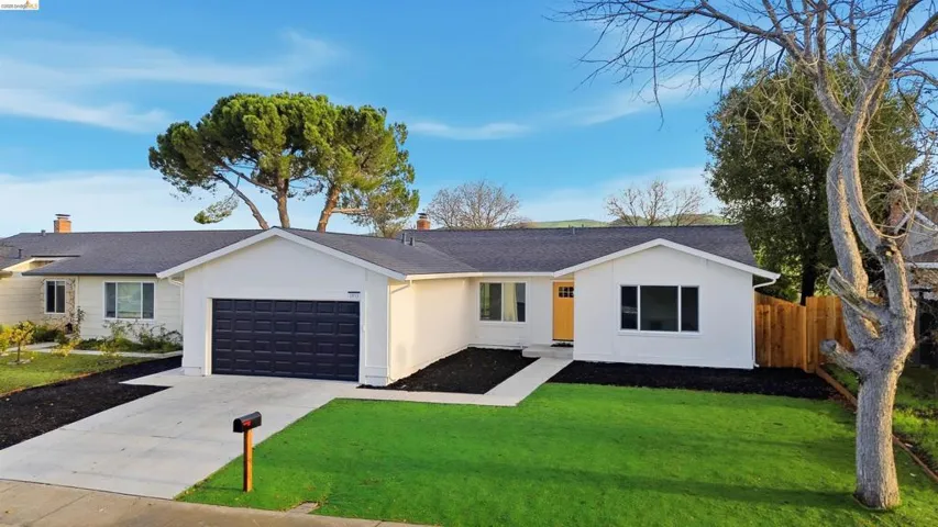 Ranch-style house featuring driveway, roof with shingles, an attached garage, and a chimney