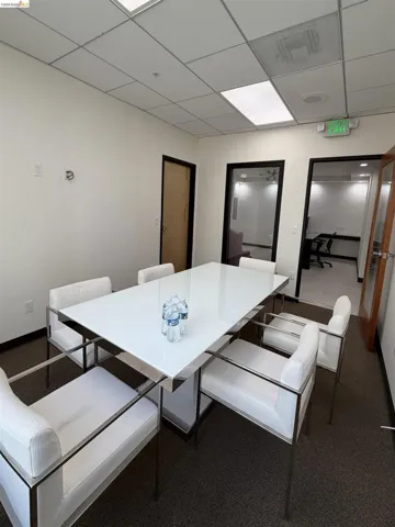 Carpeted dining area with a paneled ceiling and baseboards