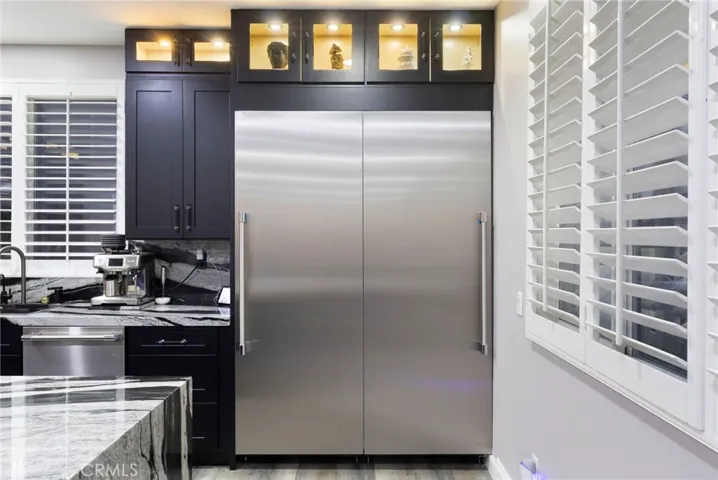 60 inch premium commerical Thermador fridge and freezer. Dishwasher depicted to the left of custom light up cabinetry.