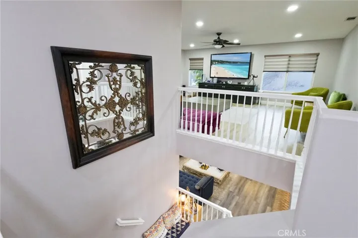Above the stair case, looking straight at the giant loft area with ceiling fan.
