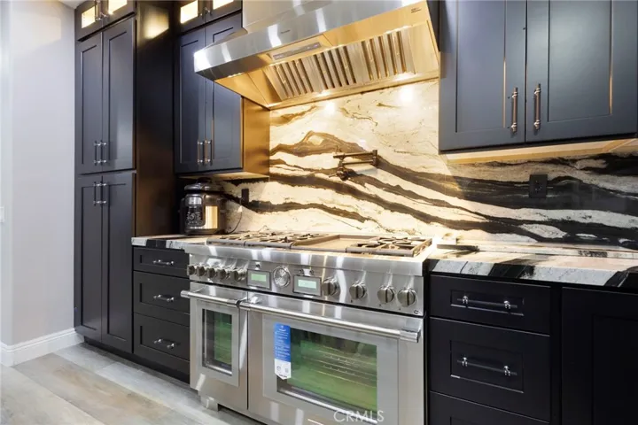 Chef’s kitchen featuring a Thermador 8-burner range, pot filler, dual ovens, and 48" hood and expansive storage cabinetry with under cabinet lighting.