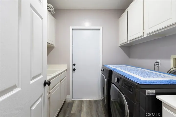 Large laundry room with sink. Door leads to the side of the house, allowing for easy access to and from the pool. Guests can use this door to go straight into the downstairs bathroom, removing excess dirt and water spillage throughout the home on days the pool is being utilized.