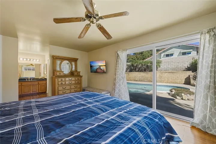 Roomy primary  bedroom with ceiling fan and sliders to the pool and hot tub. En suite in the distance.