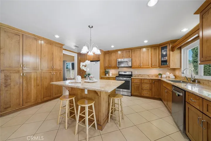 An inviting updated kitchen, at one time, reimagined with extra cabinets for pantry needs and room to enjoy as extra living room. Island in the middle is a great gathering hub with granite counters.