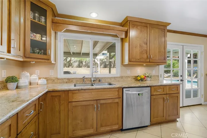 Beautiful cabinets and granite counters. Sink overlooks the covered patio. French doors show the pool in the distance.