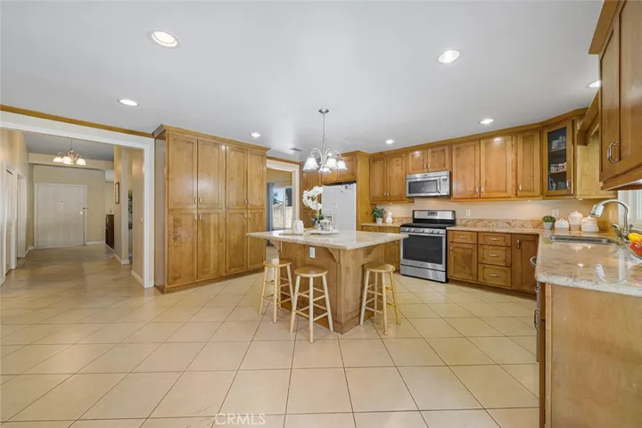 An inviting updated kitchen, at one time, reimagined with extra cabinets for pantry needs and room to enjoy as extra living room. Island in the middle is a great gathering hub with granite counters. Throughway to the left leads to the formal entry and hallway to the bedrooms and bathrooms.